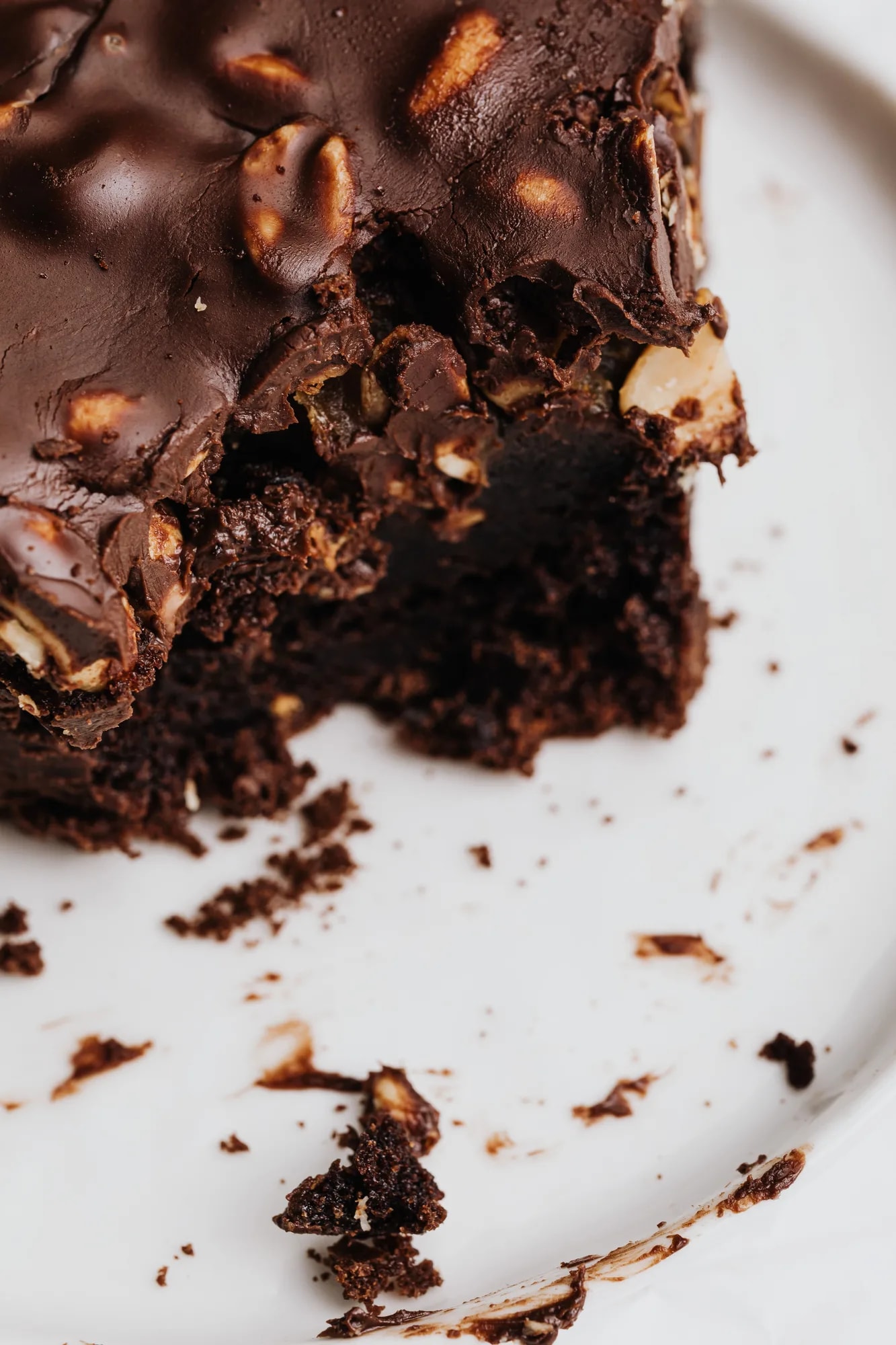 A chocolate brownie topped with nuts on a white ceramic plate