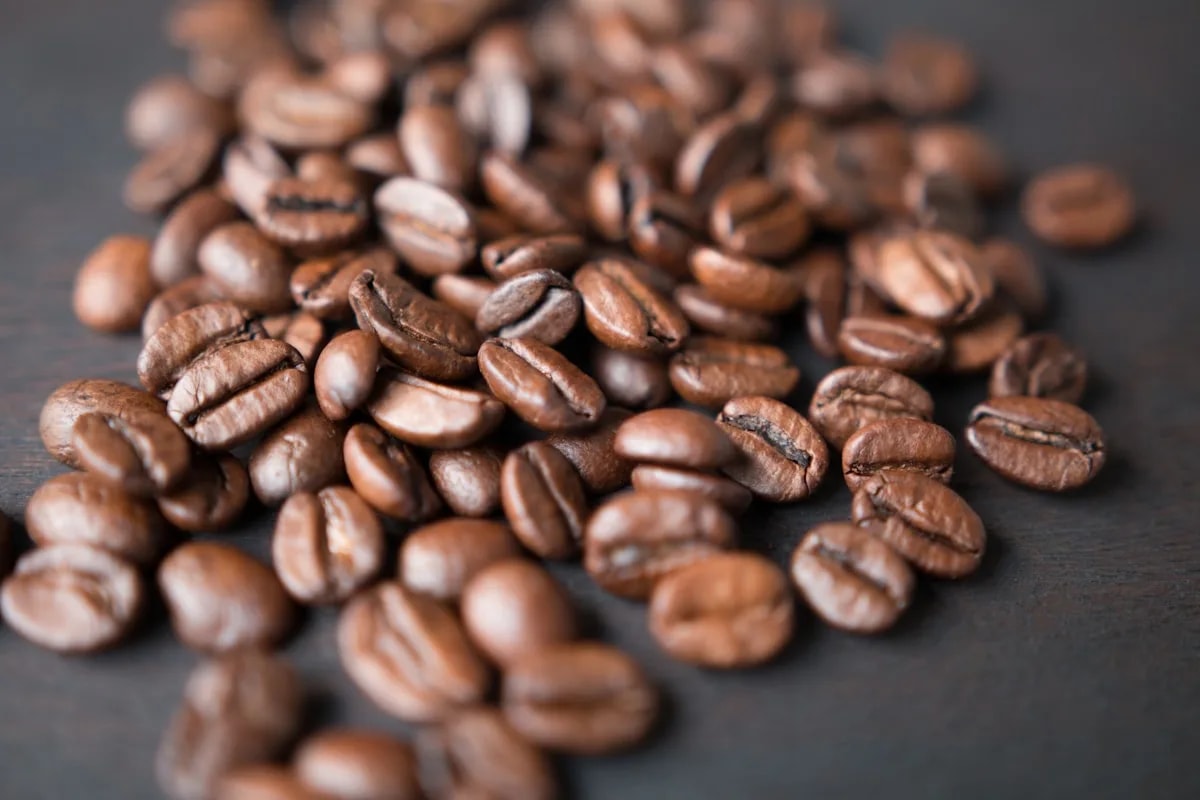 Close-up of roasted coffee beans with shallow depth of field on a dark wooden surface