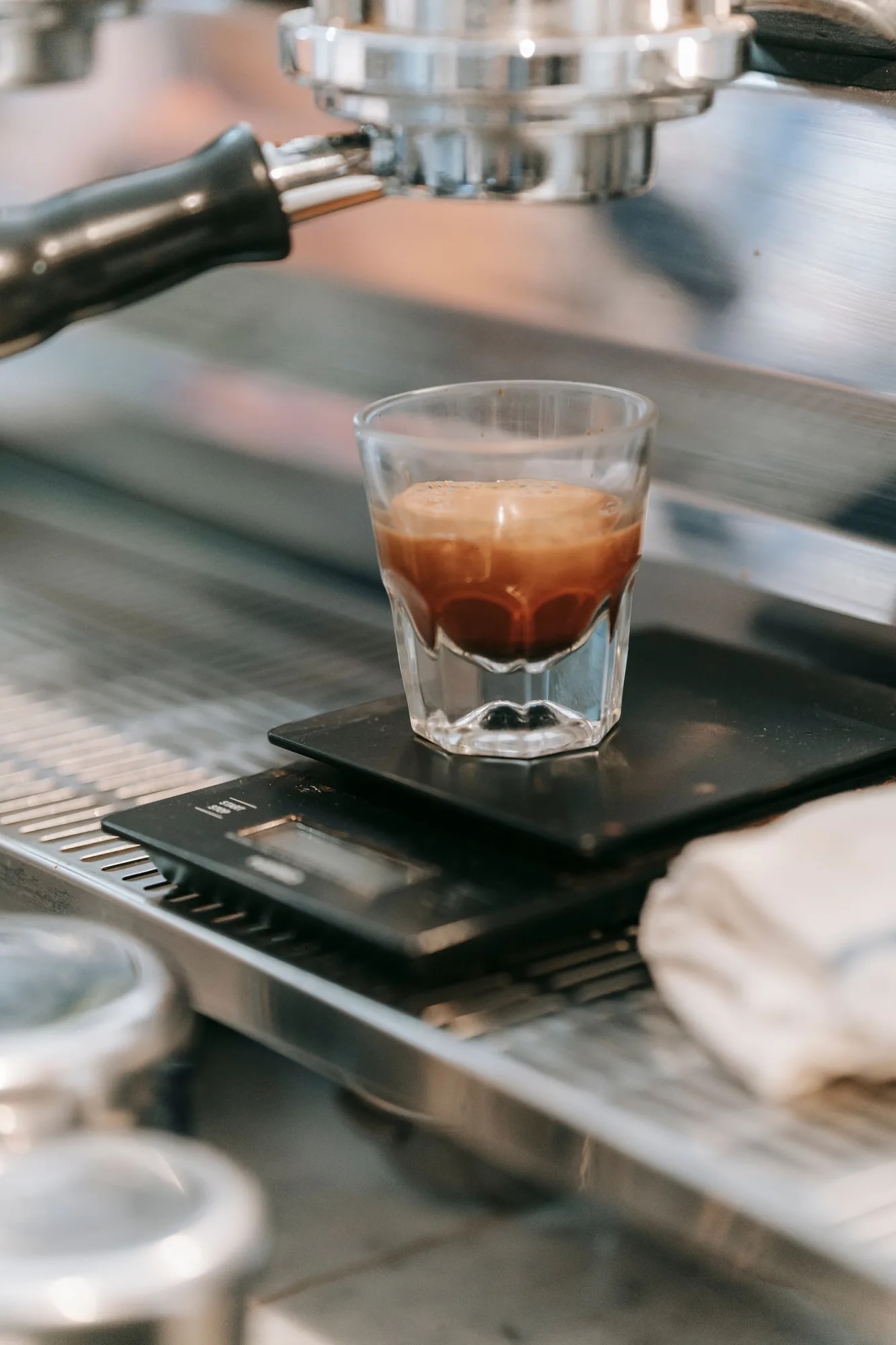 Close-up of a fresh espresso shot being extracted from a machine into a small glass