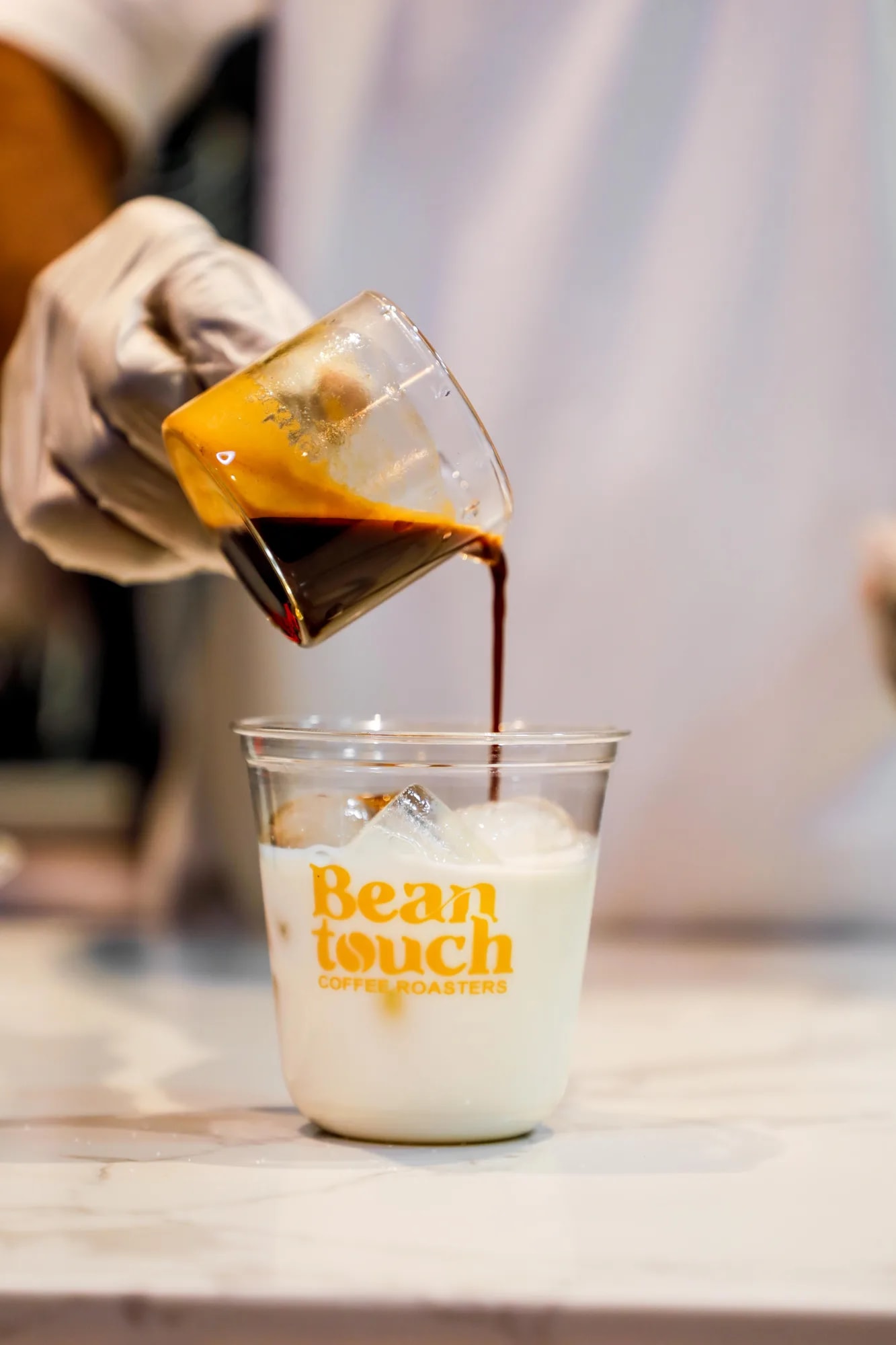 Iced coffee drink being poured over ice in a glass
