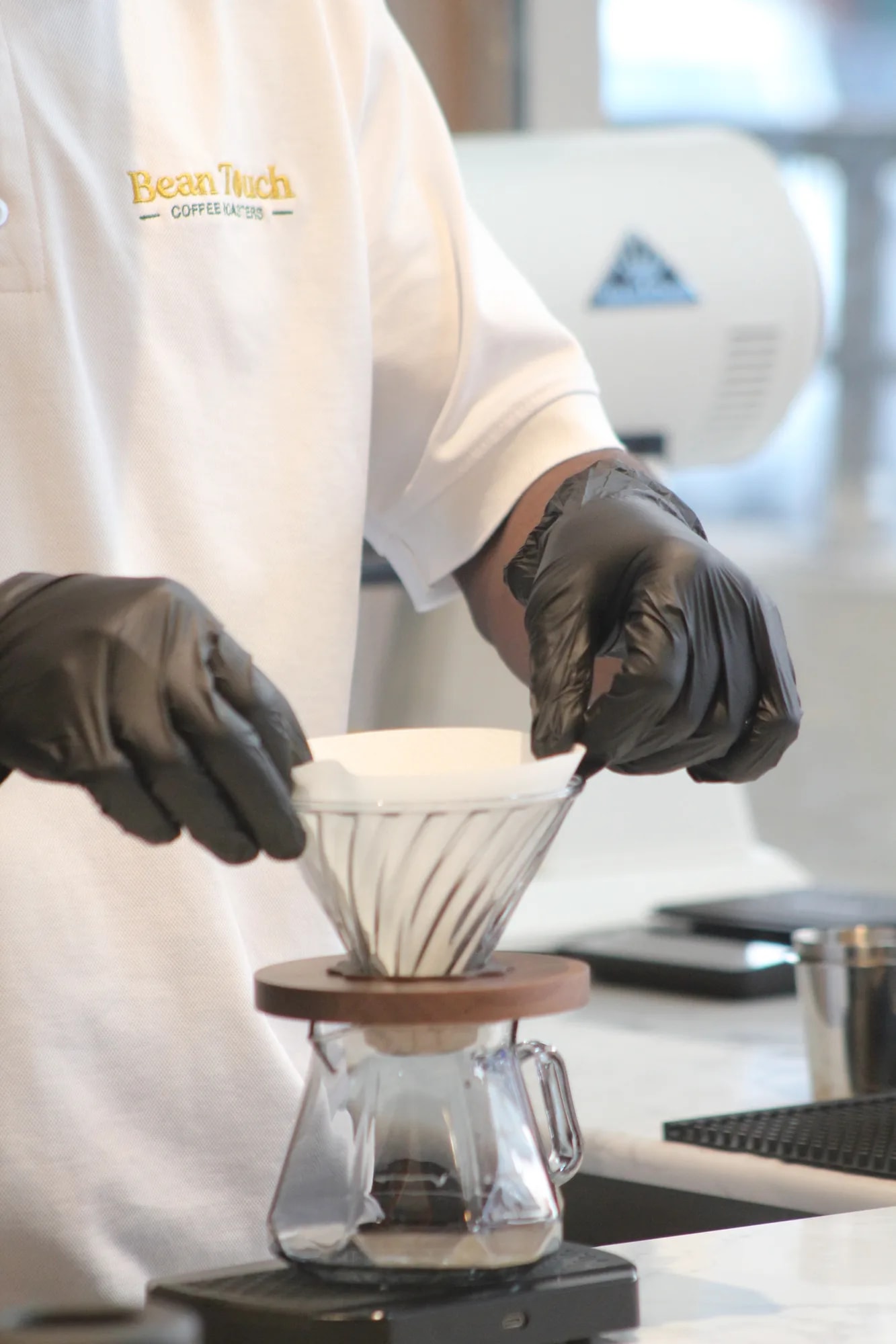 Barista hand-pouring hot water over a V60 dripper during a pour-over brew