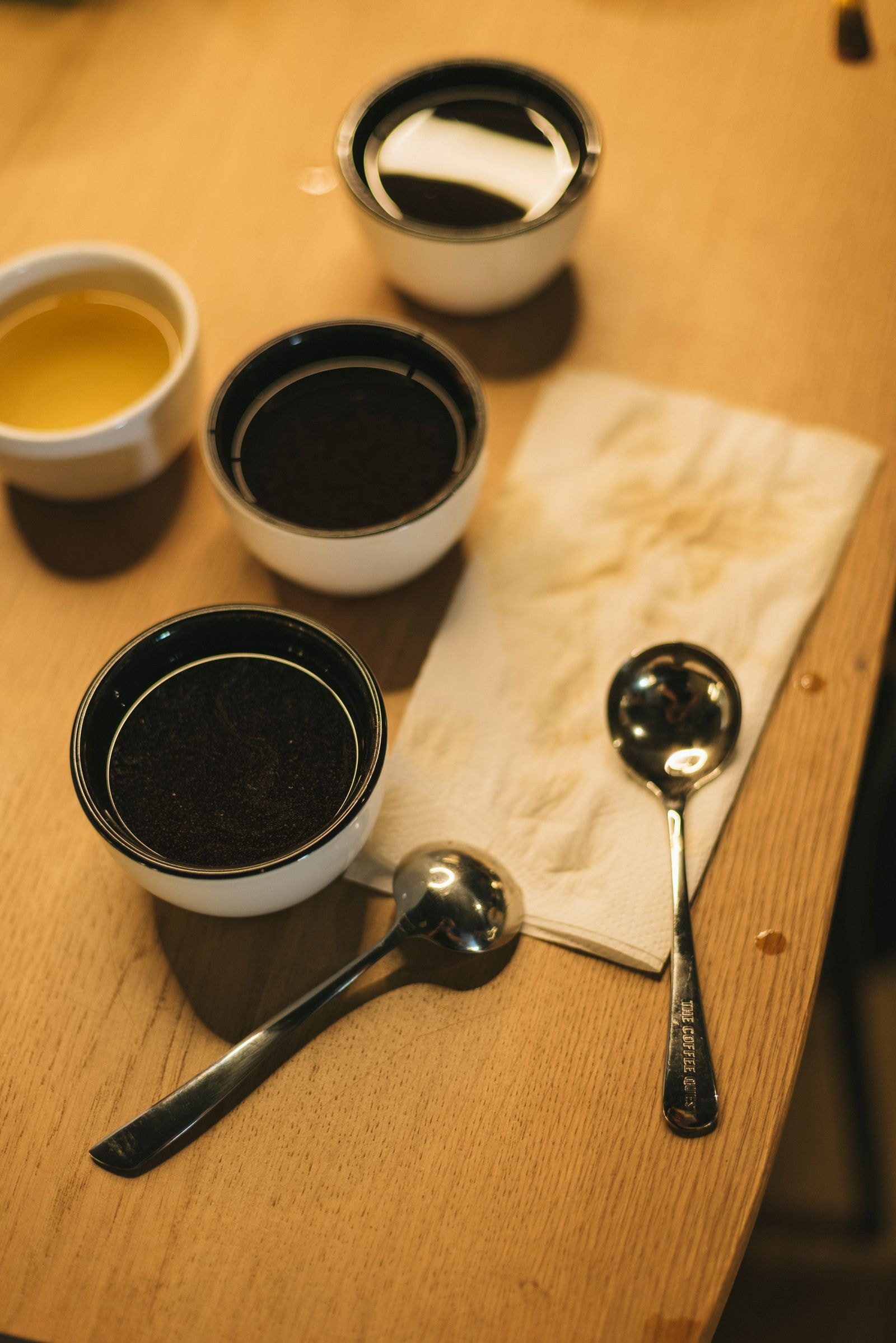 Coffee cupping tasting setup with cups and spoons arranged on a wooden table